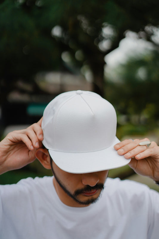 Person wearing a white cap with a blurred natural background