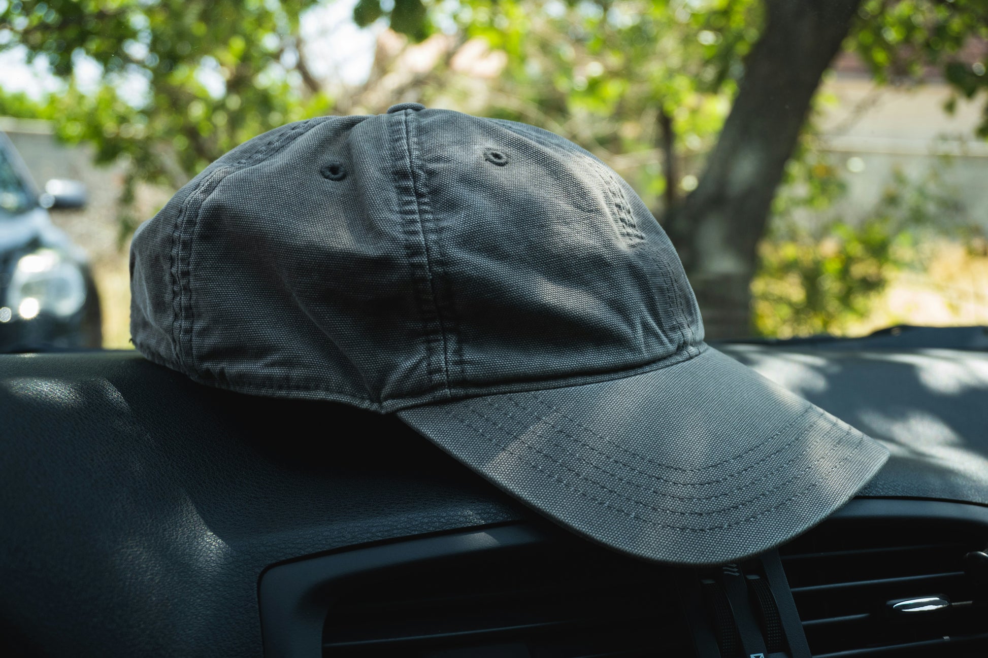 Black cap on a car dashboard with a blurred outdoor background